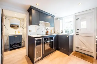 a kitchen with dark blue cabinets and a sink at Norsey Cottage Billericay in Billericay