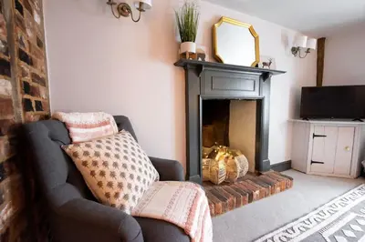 a living room with a couch and a fireplace at Norsey Cottage Billericay in Billericay