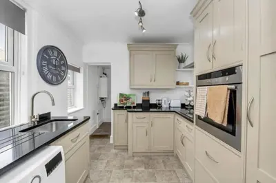 a kitchen with white cabinets and a clock on the wall at Wherstead Rd House By Homestyles Hosts Short Lets & Serviced Accommodation Suffolk With Free Parking in Ipswich
