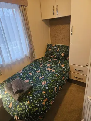 a small bedroom with a bed with flowers on it at Lakeside mini lodge in Saint Osyth
