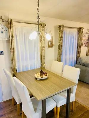a dining room with a wooden table and white chairs at Lakeside mini lodge in Saint Osyth
