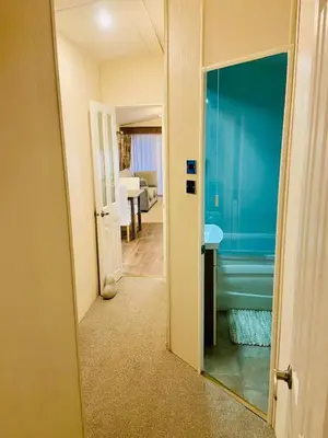 a hallway with a bathroom with a sink and a mirror at Lakeside mini lodge in Saint Osyth