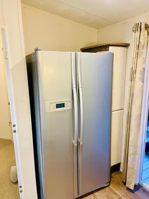 a stainless steel refrigerator in the corner of a kitchen at Lakeside mini lodge in Saint Osyth