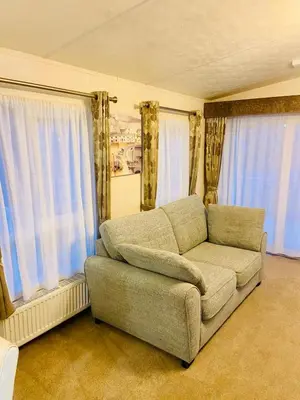 a living room with a couch in front of windows at Lakeside mini lodge in Saint Osyth