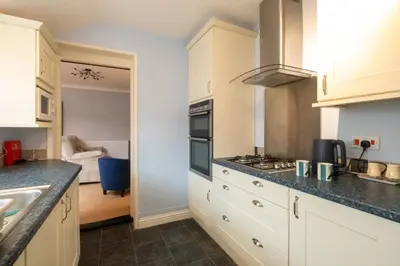 a kitchen with white cabinets and a stove top oven at 10 Jubilee Cottage in Leiston