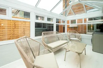 a screened in porch with two chairs and a table at 10 Jubilee Cottage in Leiston