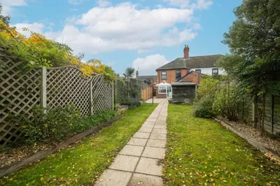 a walkway in a yard next to a fence at 10 Jubilee Cottage in Leiston