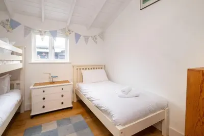 a bedroom with two beds and a bunk bed at 3 Uplands, Thorpeness - Sleeps 3, Close to Beach, Boating Lake, Thorpeness Golf Club and Country Club - Aldeburgh Coastal Cottages in Thorpeness
