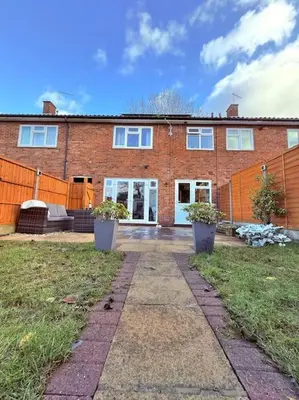 a brick house with two potted plants in front of it at Three bedroom house in Harlow