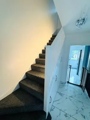 a staircase in a home with white walls and a stair case at Three bedroom house in Harlow