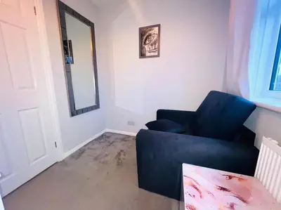 a living room with a blue chair and a mirror at Three bedroom house in Harlow