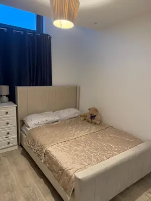 a teddy bear sitting on a bed in a bedroom at Station stay in Harlow