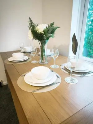 a table with plates and glasses and a vase of flowers at Comfortable 2-Bed Home, Perfect for Work and Leisure in Colchester in Colchester