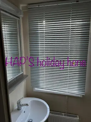a bathroom with a sink and a window with a happy holiday note at HAPs Holiday Home - Haven The Orchards in Brightlingsea