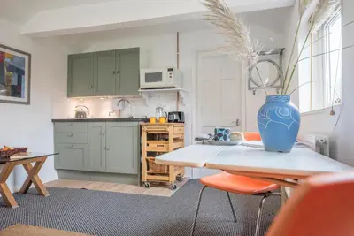 a kitchen with a table with a blue vase on it at 2 Lion Cottages, Knodishall in Leiston