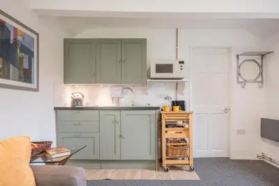 a kitchen with green cabinets and a microwave at 2 Lion Cottages, Knodishall in Leiston