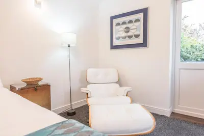 a room with a bed and a chair and a window at 2 Lion Cottages, Knodishall in Leiston