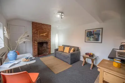 a living room with a couch and a fireplace at 2 Lion Cottages, Knodishall in Leiston