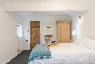 a bedroom with a white bed and a wooden chair at 2 Lion Cottages, Knodishall in Leiston