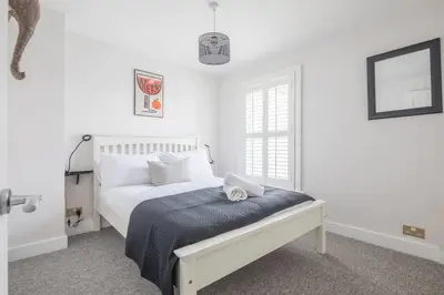 a white bedroom with a bed and a window at Beautiful 2Bed cottage nr City in Cambridge