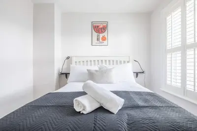 a white bedroom with a bed with towels on it at Beautiful 2Bed cottage nr City in Cambridge