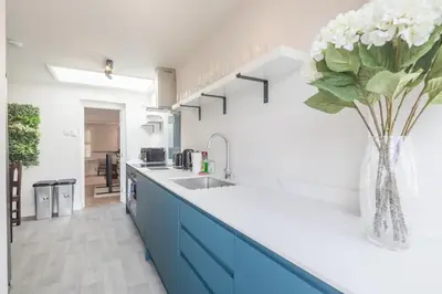 a kitchen with blue cabinets and a vase of flowers at Beautiful 2Bed cottage nr City in Cambridge