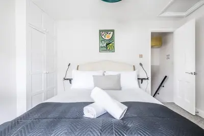 a white bedroom with a large bed with two pillows at Beautiful 2Bed cottage nr City in Cambridge