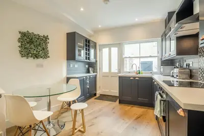 a kitchen with blue cabinets and a glass table at Beautiful 2bed Central Home in Cambridge