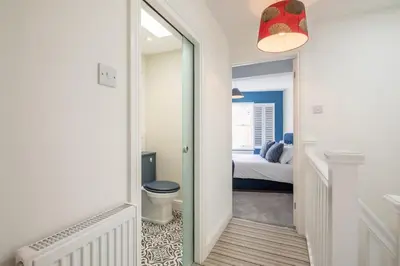 a hallway with a bathroom with a toilet and a mirror at Beautiful 2bed Central Home in Cambridge