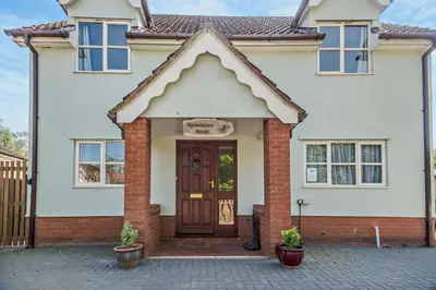 a white house with a brown door at 4 Bed in Woodbridge oc-s27356 in Martlesham