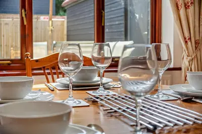 a wooden table with wine glasses and plates on it at 4 Bed in Woodbridge oc-s27356 in Martlesham