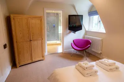 a bedroom with a purple chair and a bed at Hill House Norfolk in Saxlingham Nethergate