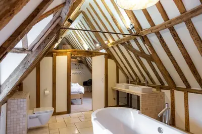 a bathroom with a white bath tub in a attic at Hill House Norfolk in Saxlingham Nethergate