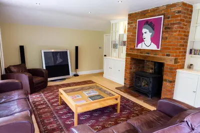 a living room with a couch and a fireplace at Hill House Norfolk in Saxlingham Nethergate