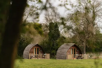 two small huts in a field with trees at Maglia Rosso by Wigwam Holidays in Bury Saint Edmunds