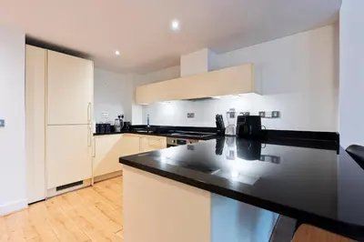 a kitchen with a black counter top and white cabinets at Luxurious City Centre Cosy WiFi and Netflix in Chesterton