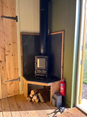 a stove in the corner of a room at Bramley Cabin Suffolk Relaxing Getaway in Woodbridge