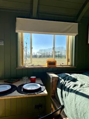 a room with a table with two plates and a window at Bramley Cabin Suffolk Relaxing Getaway in Woodbridge