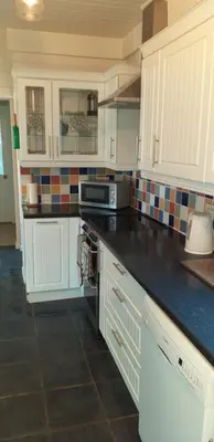 a kitchen with white cabinets and a black counter top at Crow Corner in Yoxford