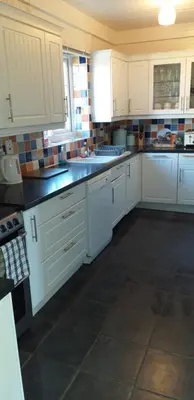a kitchen with white cabinets and a black counter top at Crow Corner in Yoxford