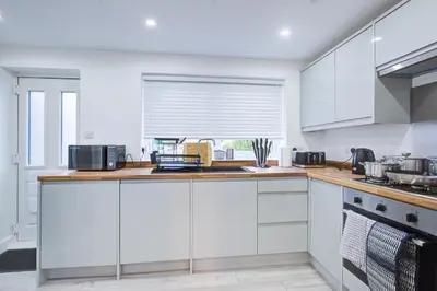 a white kitchen with white cabinets and a window at Sleek 3 Bedroom Home Sleeps 6 with Parking in Colchester