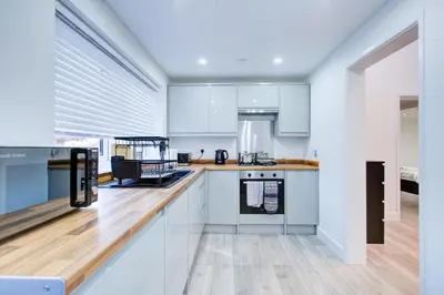 a kitchen with white cabinets and a wooden counter top at Sleek 3 Bedroom Home Sleeps 6 with Parking in Colchester