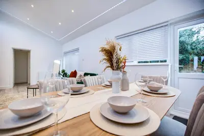 a dining room with a table with plates and wine glasses at Sleek 3 Bedroom Home Sleeps 6 with Parking in Colchester