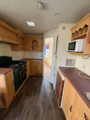 a kitchen with wooden cabinets and a black stove top oven at The static, it is what it is! in Wicken