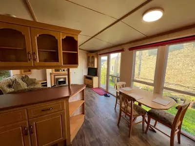 a kitchen with a table and chairs and some windows at The static, it is what it is! in Wicken