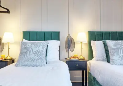 two beds with green headboards in a bedroom at Well-Located 4 Bed Property in Colchester, Suited for Families and Business Travelers in Colchester