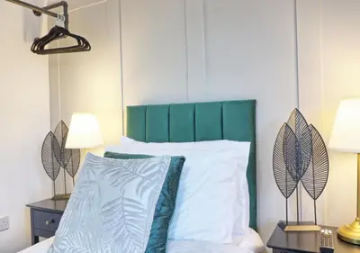 a bedroom with a bed with a green headboard and two lamps at Well-Located 4 Bed Property in Colchester, Suited for Families and Business Travelers in Colchester