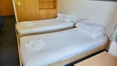 two beds in a room with white sheets and pillows at Sidney Sussex College, Cambridge in Cambridge