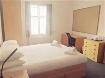 a bedroom with two beds and a desk and a mirror at Sidney Sussex College, Cambridge in Cambridge