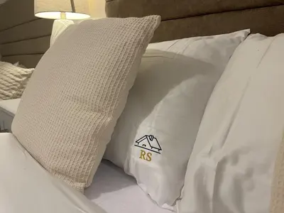 a bed with white pillows and a pillow with rsa on it at The Comfort, with Free Parking, Harlow in Harlow
